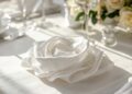 Servietten Blumen basteln für Hochzeit – zur Rose gefaltete Serviette auf festlicher Tafel